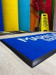 Logolu kapı önü paspasın yakın çekim baskı detayı, uzun ömürlü ve kaliteli malzeme